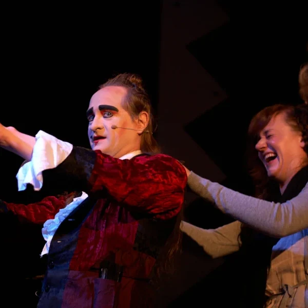 Le Comte interaktiver Zeremonienmeister Ein Schauspieler in einem roten Kostüm führt mit einer lächelnden Frauenfigur auf der Bühne.